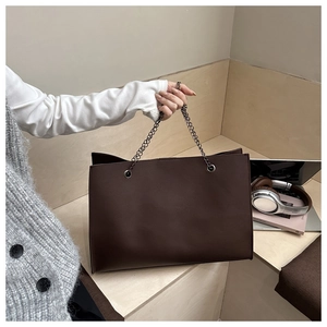Détail de la texture d'un grand sac cabas marron chocolat avec anses en chaîne gris foncé
