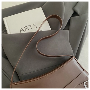 Detailed macro view of a vintage brown leather bag with silver buckle on a blazer