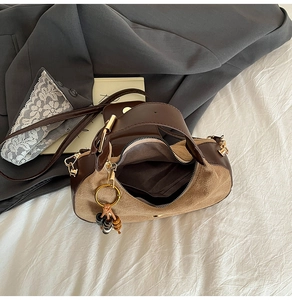 Detail view of brown suede crescent bag with gold zipper and wooden bead charm