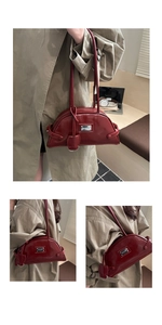 Detail view of a dark red patent leather crescent bag with metallic logo plate