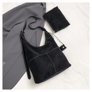Detail of black tote bag with white contrast stitching and a matching pouch on fabric