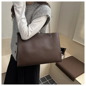 Sac fourre-tout marron avec chaîne porté à l'épaule par un mannequin en intérieur