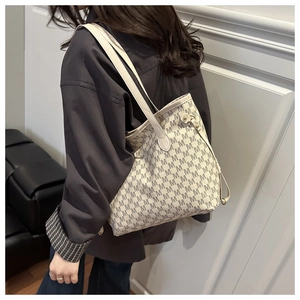 Detail of a large tote bag featuring vintage grey letter print and metallic rivet accents