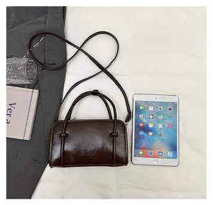 Detailed size comparison of brown faux leather Boston bag next to an iPad on beige fabric