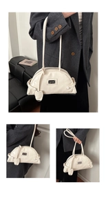 Detail of a white patent leather half-moon bag featuring a metallic nameplate on the front