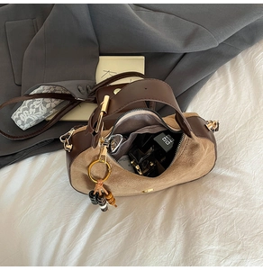 Close-up of minimalist suede crossbody bag with decorative beads and gold zipper detail