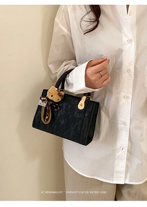 Détail d'un sac à main en velours côtelé noir avec fermoir doré et breloque