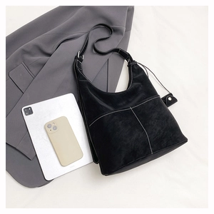 Detail of black suede tote bag with white contrast stitching and magnetic snap closure
