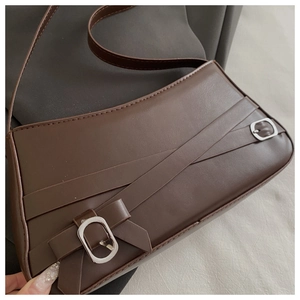 Detail of dark brown faux leather shoulder bag featuring silver oval metal buckles