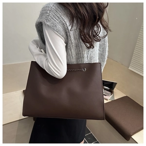 Vue détaillée du grand sac cabas marron foncé avec texture cuir et bandoulière en chaîne