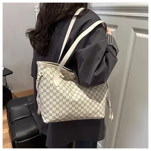 Detail of monogram tote bag featuring gray M-pattern and gold-tone drawstring hardware