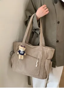 Détail du sac fourre-tout en velours côtelé kaki avec cordon de serrage et breloque ours