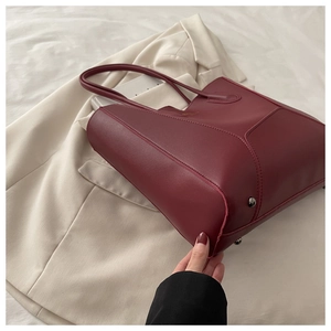 Détail du sac cabas bordeaux avec coutures géométriques et pieds de sac en argent