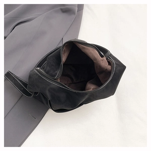 Detail of black tote bag with white stitching, brown lining and secure zipper closure