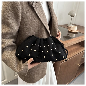 Dettaglio di una borsa a mano in pelle scamosciata nera con borchie dorate e coulisse