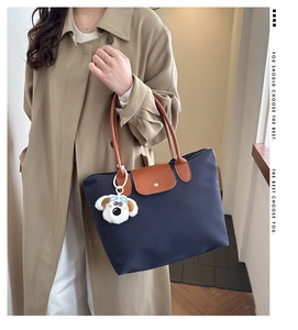 Detail of navy nylon tote bag with leather flap, handles and cute puppy plush charm