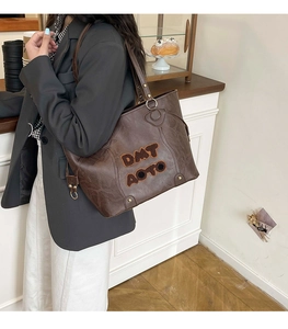 Detail of vintage brown tote bag with fuzzy DMT AOTO lettering and metal ring detail