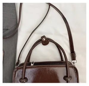 Detail of dark brown faux leather bag with round handles and metal zipper closure