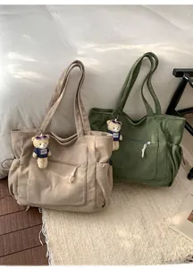 Détail de cabas en velours côtelé kaki et vert foncé avec breloques oursons