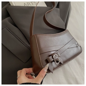 Detail of dark brown retro underarm bag with criss-cross leather patterns and metal buckles