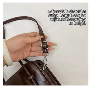 Detail of adjustable dark brown faux leather shoulder strap with silver metal buckle