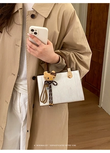 Détail du sac à main blanc texturé avec poignée marron et charmant pendentif en peluche