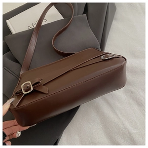 Detail view of dark brown retro shoulder bag featuring silver metal buckle straps