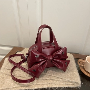 Burgundy handbag with a large bow and star rivets shown from a 45-degree angle