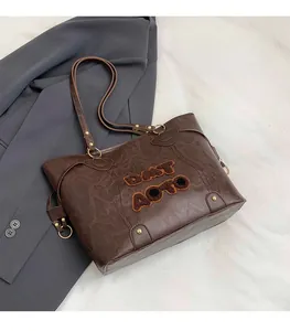 Close-up of caramel brown tote bag with embossed leather texture and flocked lettering