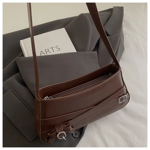Detail of brown vintage shoulder bag featuring metallic buckle and bow tie on leather