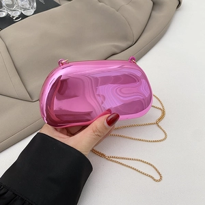 Detail of a shiny metallic pink hard-shell clutch bag with a delicate gold chain strap