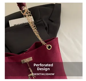 Detail of burgundy frosted suede handbag with gold chain strap and deer pendant