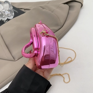 Detail of metallic pink heart-shaped clutch bag with golden chain strap for women