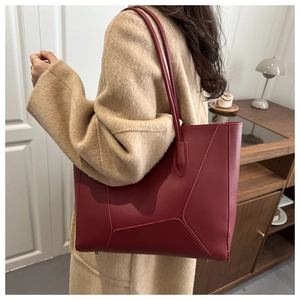 Détail du sac cabas en cuir rouge foncé avec coutures géométriques sur un mannequin