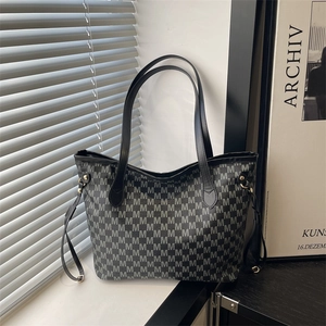 Chic grey tote bag with M letter prints and black handles on a modern windowsill