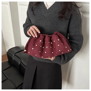 Dettaglio della borsa pochette bordeaux in camoscio con borchie dorate e chiusura a cordoncino