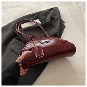 Detail view of wine red patent leather dumpling bag with glossy finish and metal hardware