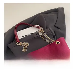 Close-up of metal chain and burgundy suede shoulder strap on a retro tote bag