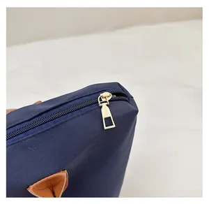 Close-up of polished gold-tone zipper and navy blue durable fabric on large tote bag