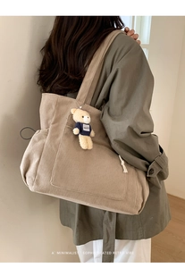 Detail of beige corduroy tote bag featuring a front pocket and cute teddy bear charm