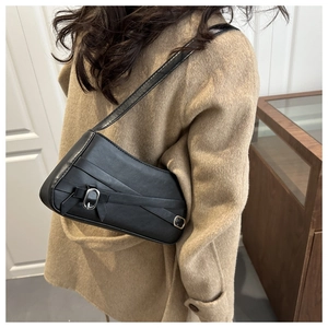 Model wearing a vintage black leather underarm bag with silver buckle over a camel coat