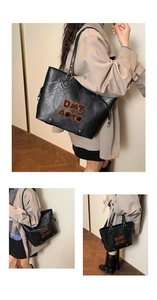 Detail of a large black tote bag with DMT AOTO lettering and metal studs on the bottom
