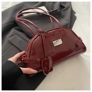 Close-up of deep red patent leather dumpling bag with silver hardware and chic straps