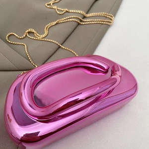 Close-up of pink metallic textured clutch bag with unique circular handle and gold chain