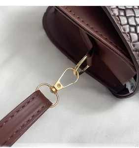 Detail of dark brown woven leather texture with shiny gold metal hook and neat stitching