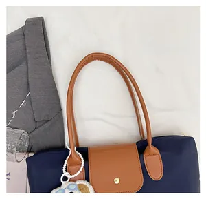 Detail of blue nylon tote bag with brown leather handles and a cute dog plush charm