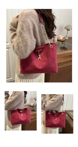 Detailed macro view of burgundy suede handbag with golden reindeer charm and chain strap
