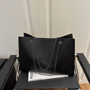 Grand sac cabas noir texture lychee avec bandoulières chaîne argentées sur chaise