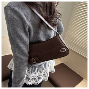 Side view of a vintage dark brown leather underarm bag with silver buckles on a model