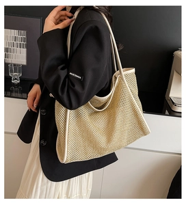 Close-up of a woven straw tote bag featuring cream leather trim and reinforced stitching
